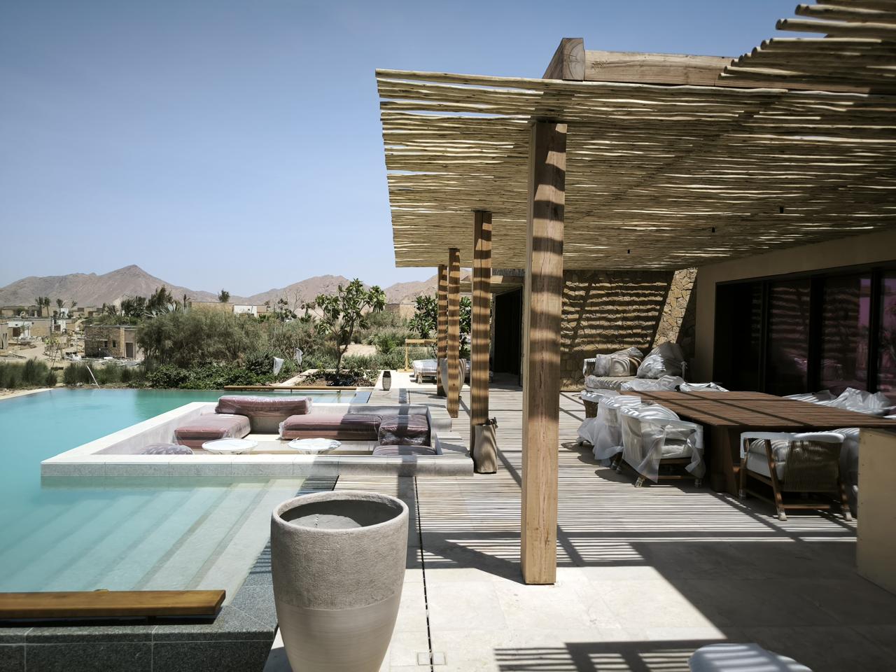 Desert retreat terrace with a pool and timber shade structure