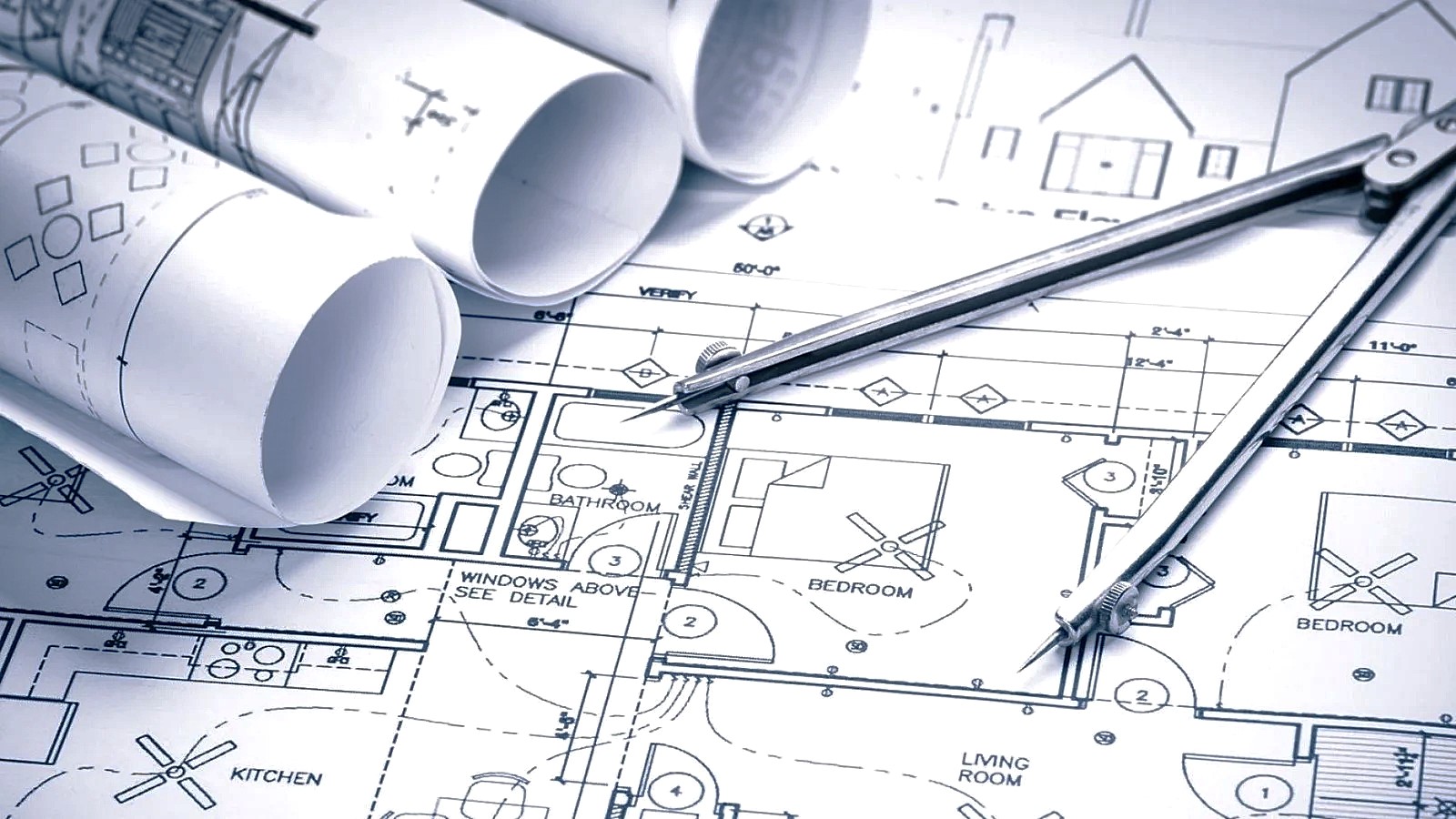 Architectural floor plans, rolled drawings and a pair of dividers on a drafting table