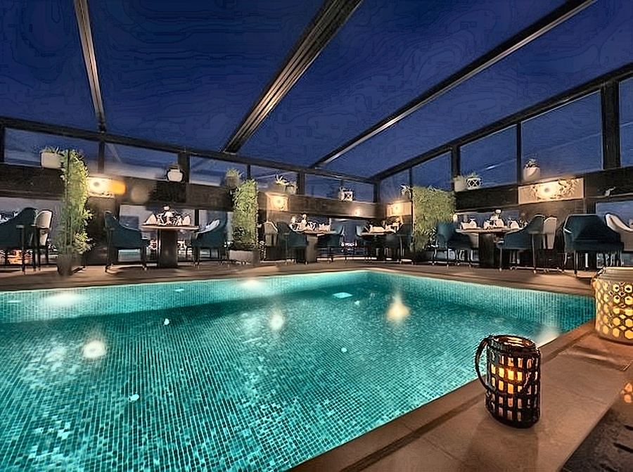 Rooftop pool under a glazed canopy at night